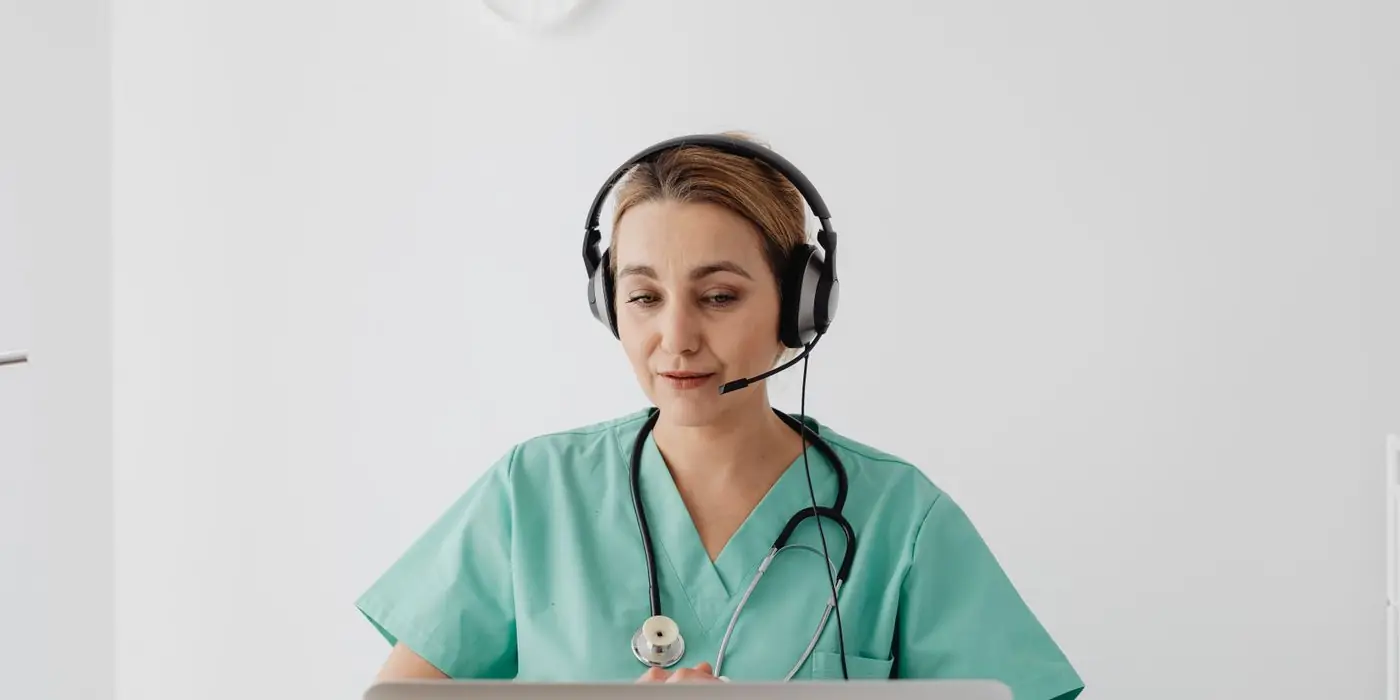 A clinician with a headset working on a laptop