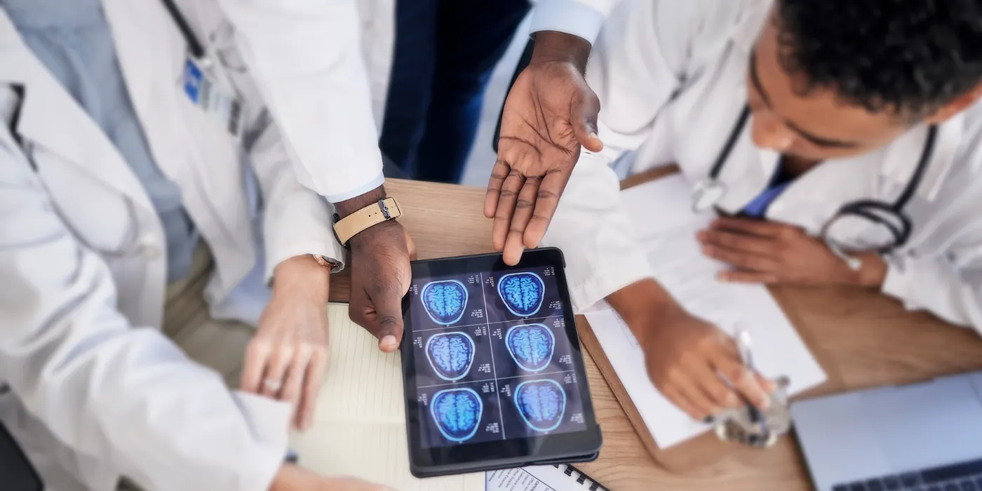Doctors reviewing brain scans on a tablet around a table
